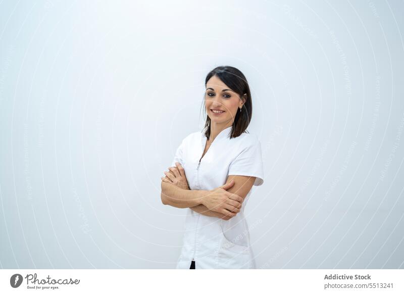 Cheerful woman in medical uniform with arms folded doctor smile hospital clinic arms crossed friendly work professional specialist medicine cheerful job