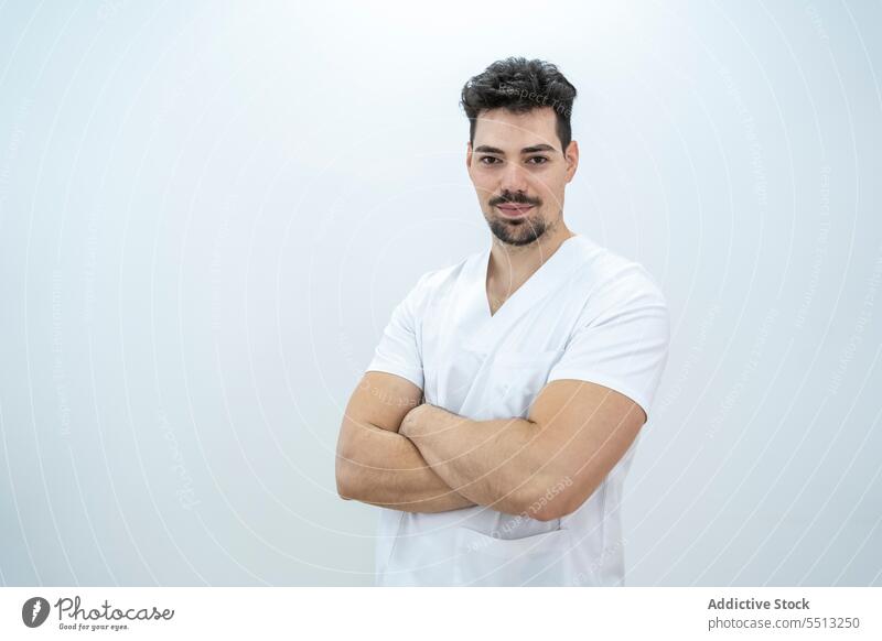 Confident man with crossed arms looking at camera doctor confident therapist arms crossed serious clinic uniform medicine professional hospital medical male