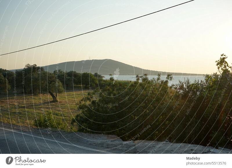 View from a bridge to the sea in the light of the evening sun with coastal landscape, bay and peninsula in Cunda near Ayvalik on the Aegean Sea in Balikesir province in Turkey