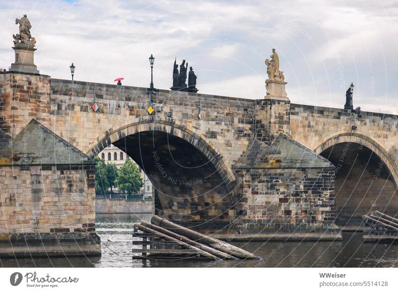 Someone walks across the famous old bridge in Prague with a red umbrella Charles Bridge The Moldau Umbrella Red Rain Weather cloudy romantic melancholically Old
