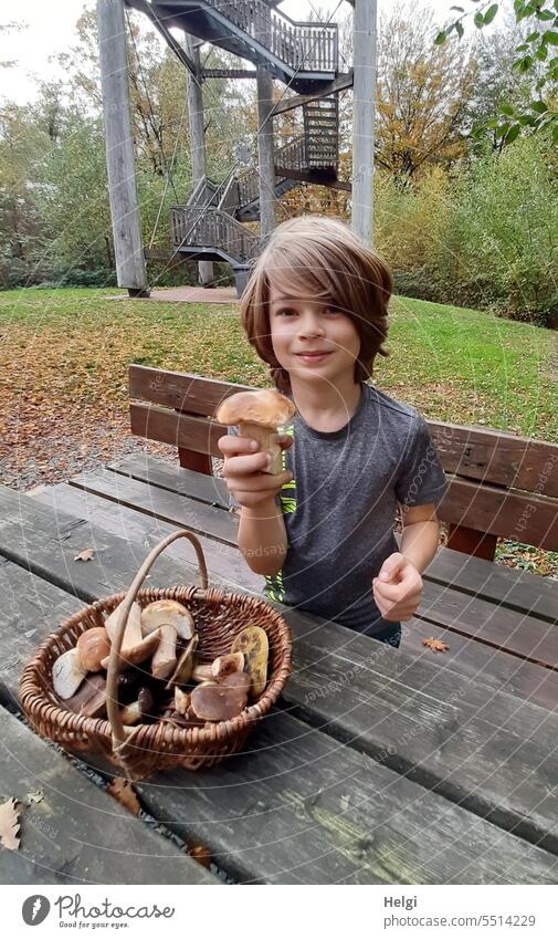 Lucky mushroom - boy holding a thick boletus mushroom in his hand, on a wooden table is a wicker basket with mushrooms Child Boy (child) Human being Basket
