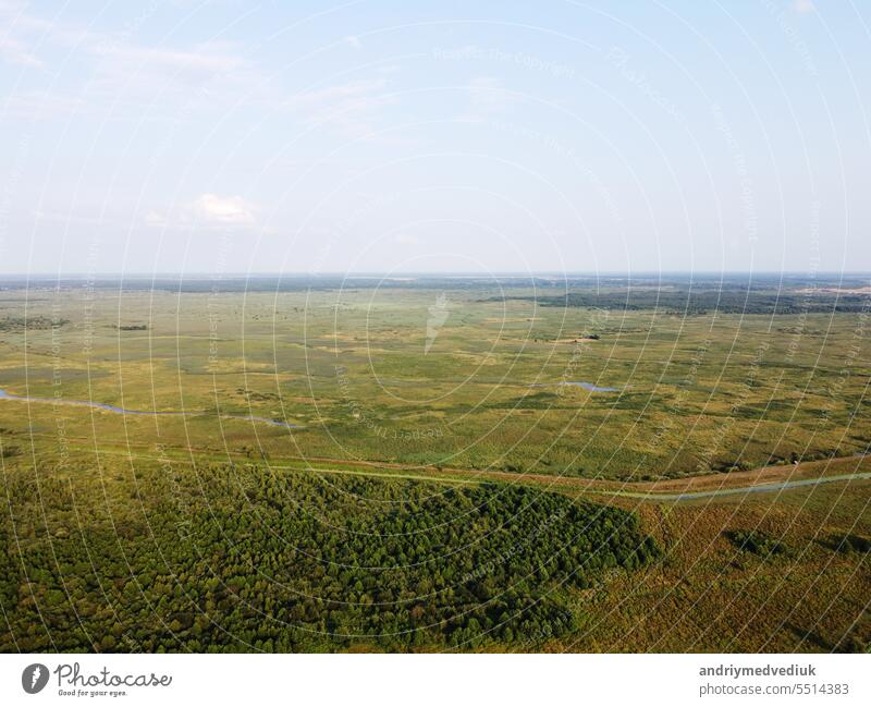 Aerial high view of rural landscape, green valley, roads, meadows, fields, trees and sky. Countryside ecotourism. Panorama of agricultural land drone shot. Concept of ecological ecosystem