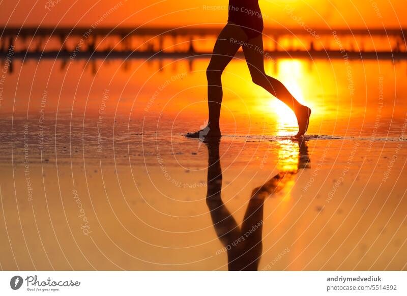 Active summer travel tropical holiday. Cropped silhouette of energy little child girls is having fun runs and plays on beach at sunset. Youth, lifestyle and happiness concept. Children's day