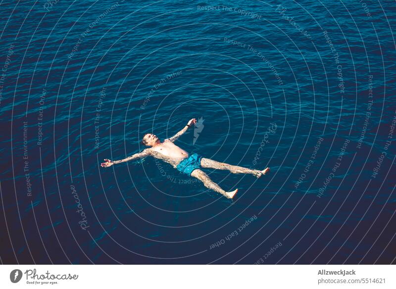 Middle aged man lying backwards in blue sea with arms and legs stretched out Ocean Oceans Water ocean Blue Swimming & Bathing bathe H2O Maritime drift Hover