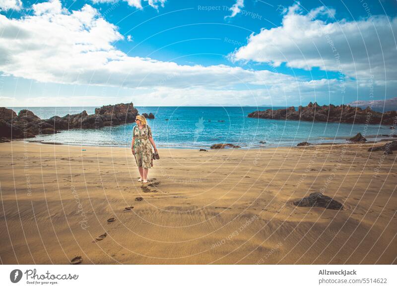 Portrait of a middle-aged woman with sunglasses and dress on a stony beach of Lanzarote portrait Short sleeve short-sleeved vacation Vacation mood