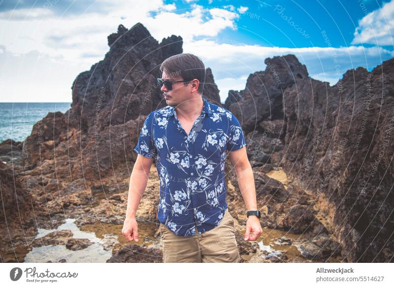 Portrait of a middle-aged man with sunglasses and blue shirt on a stony beach of Lanzarote Man portrait Short sleeve short-sleeved vacation Vacation mood