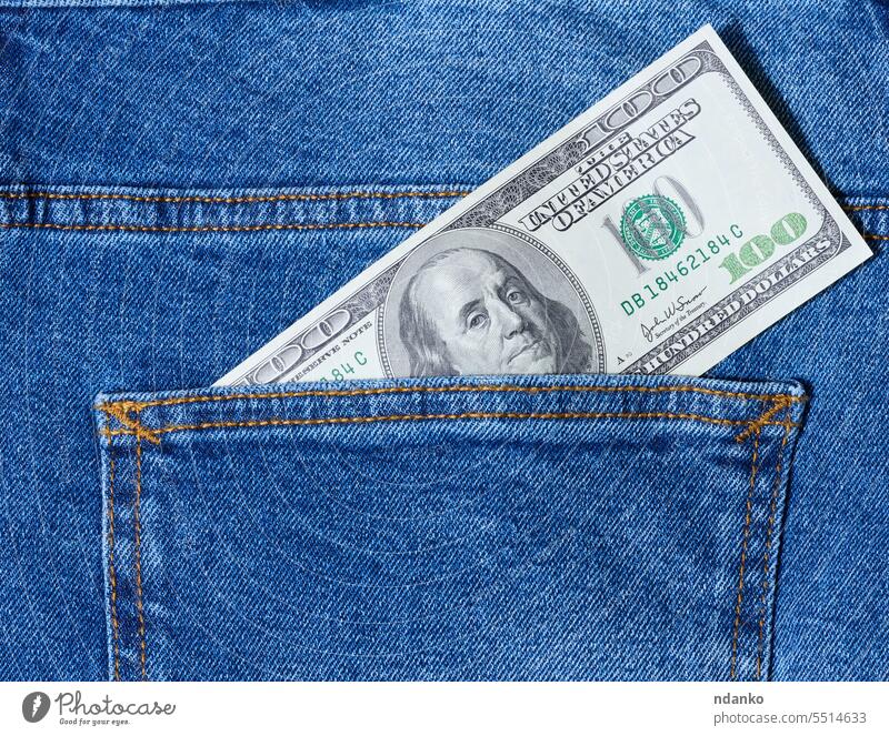 Paper American dollar bills protrude from the back pocket of blue jeans money nobody pants paper pay paying payment rich salary save success textile wealth