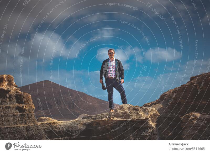Middle aged man standing on rock in front of blue sky with clouds Lanzarote Man middle-aged man posing Rock Nature outdoor ascent townspeople city people Clouds