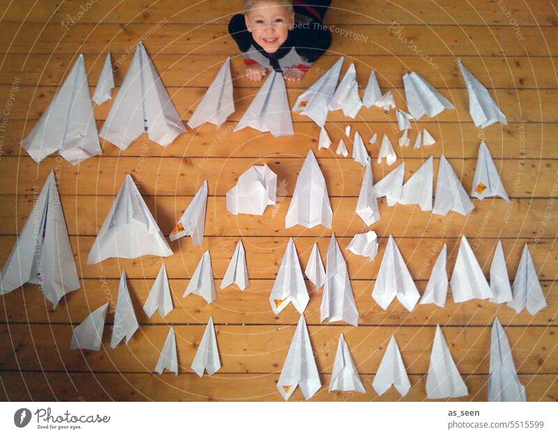 The boy with paper airplanes Paper plane Boy (child) Bird's-eye view Many test Test series Flying DIY Handicraft aviator Pride Pilot Large Small Airplane
