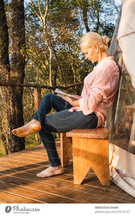Woman reading book on glamping terrace woman vacation leisure rest weekend trip lounge sunlight autumn bookworm story bench calm literature idyllic tranquil