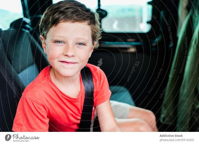 Happy cute child sitting in car with fastened seat belt in daylight boy smile happy vehicle cheerful kid preteen transport street casual positive content