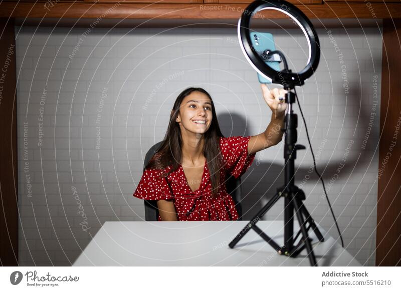 Woman recording video on smartphone in dark room woman blogger influencer live using ring lamp vlog gadget social media smile cellphone illuminate vlogger