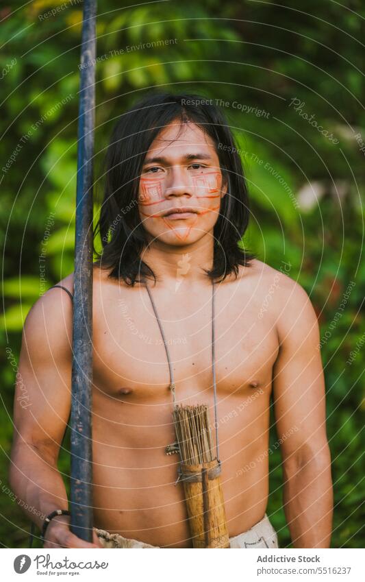Tribal man with stick in tropical forest nature serious plant green naked torso woods exotic male ethnic young tree flora environment natural foliage summer
