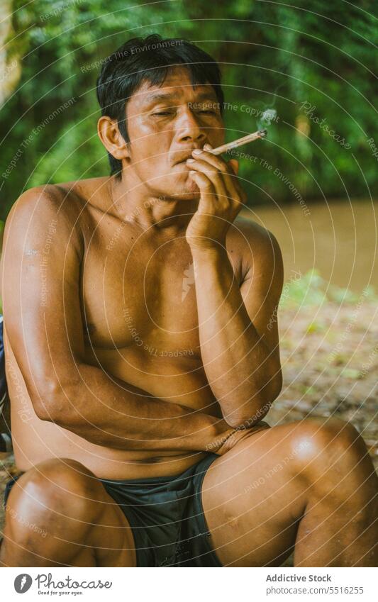 Ethnic indigenous man smoking in peace rest local nature smoke river cigarette countryside relax shore rainforest riverside fisher rural tropical coast tobacco