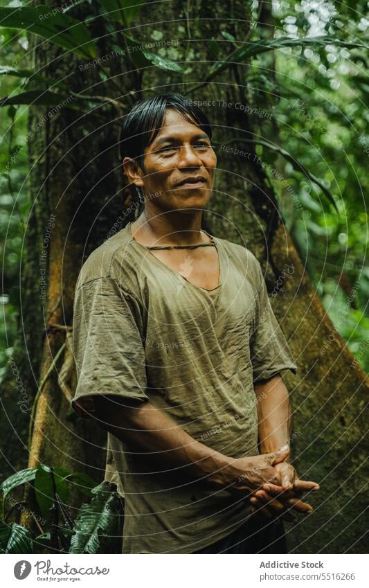 Ethnic man standing in forest tropical tribe paint exotic nature jungle green male ethnic smile glad tradition plant summer tree environment flora native woods