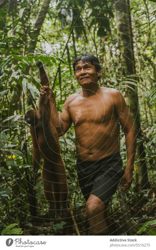 Happy ethnic man with monkey in jungle tropical cheerful nature happy plant exotic shirtless male green smile forest rainforest joy summer tree positive glad