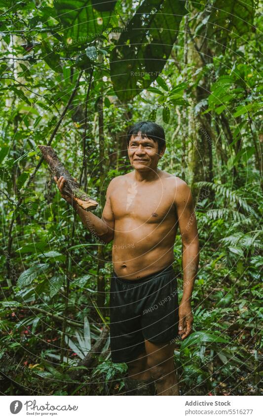 Smiling tribal man with firewood in nature jungle log collect exotic environment lumber local tribe settlement pick village national tradition culture content
