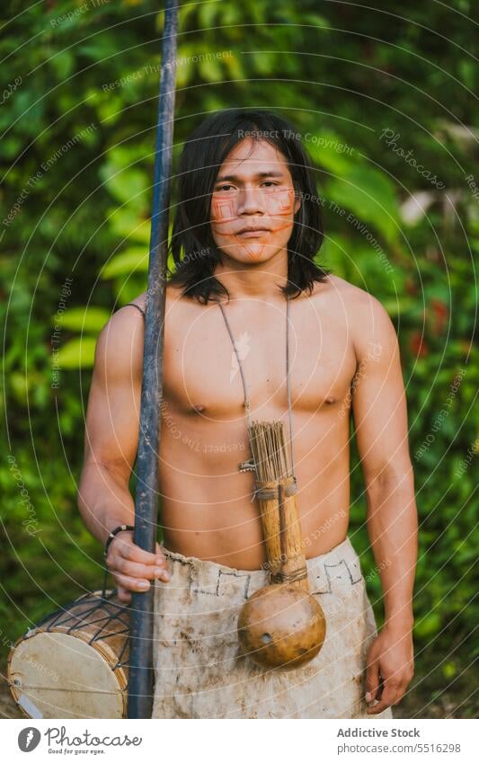 Tribal man with stick in tropical forest nature serious plant green naked torso woods exotic male ethnic young tree flora environment natural foliage summer