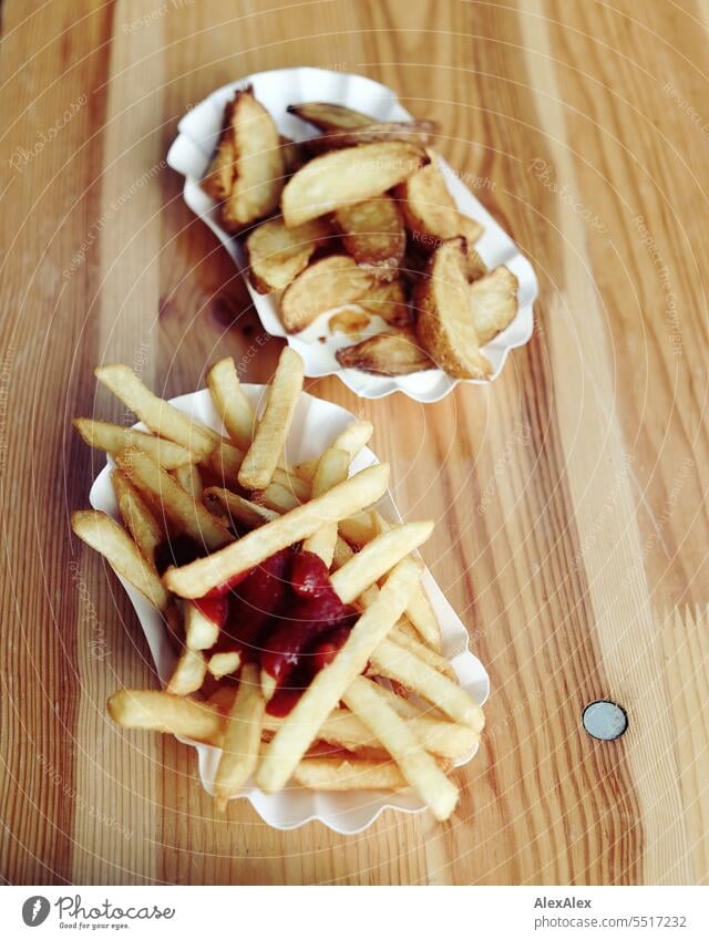 Two bowls of fries, one with chips with ketchup and one with potato wedges (wedges) and mayonnaise on a beer tent table French fries Potatoes fast food