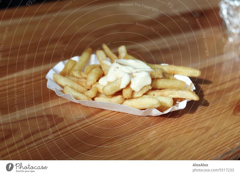 French fries with mayonnaise in a white french fries bowl on a wooden beer table Potatoes fast food Fast food Eating greasily rich kcal calories vegetarian Food