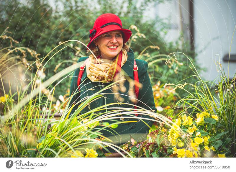 young woman with green coat and red hat among grasses and green plants Autumn Autumnal germany trip Congenial smart fashionable Exterior shot portrait Adults