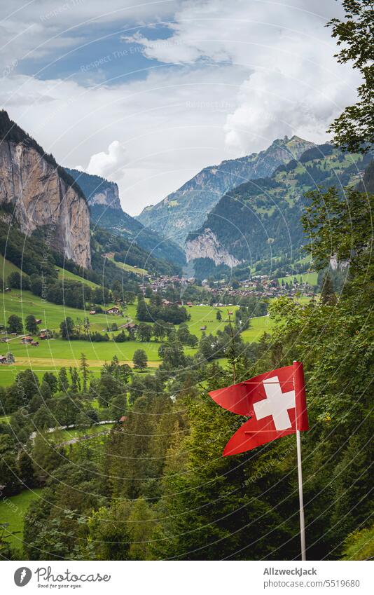 swiss flag in front of beautiful mountain panorama with view of valley in nice weather Switzerland Swiss Alps Alpine pasture Meadow Nature Green Juicy