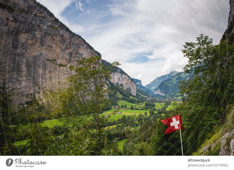 swiss flag in front of beautiful mountain panorama with view of valley in nice weather Switzerland Swiss Alps Alpine pasture Meadow Nature Green Juicy