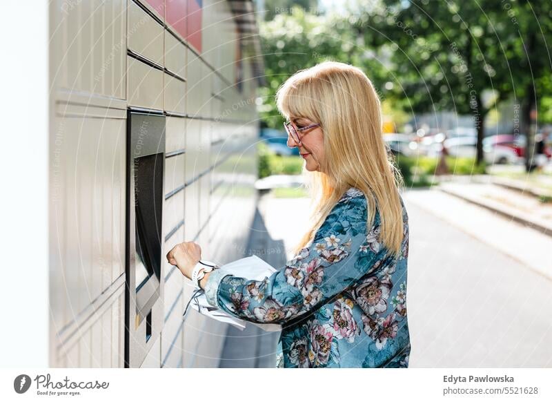 Mature woman using parcel locker in the city natural enjoy satisfied cheerful confident pensioner outdoors outside eyeglasses elderly happiness older retired