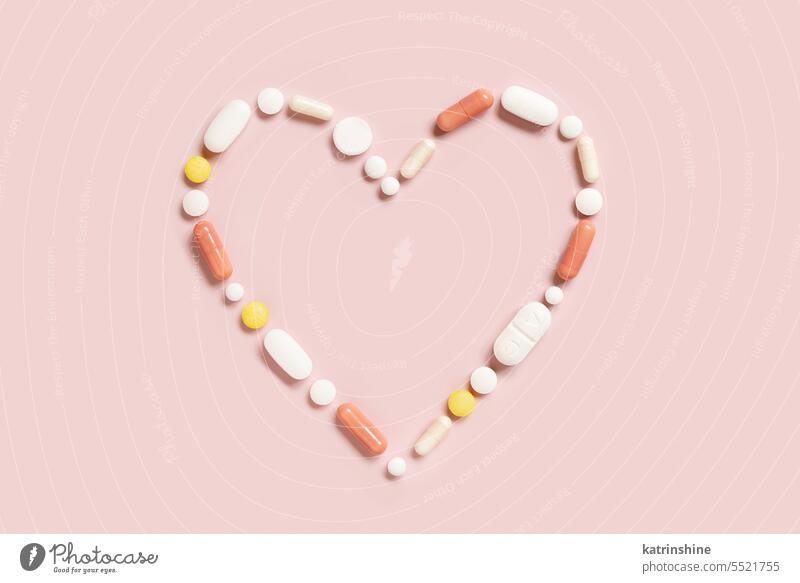 Heart shape made of colorful drug pills and capsules on light pink, top view line Pharmaceutical cardiology treatment diseases medicine medical health nutrients