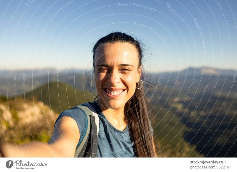 A young woman smiles at the sun from the top of a mountain near Pgasarri in the Basque Country women female person selfie basque country euskadi pagasarri