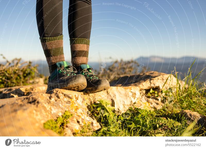 Detail of a hiker's boots, from the top of a mountain, with the natural landscape out of focus in the background nature travel adventure trek feet walk outdoors