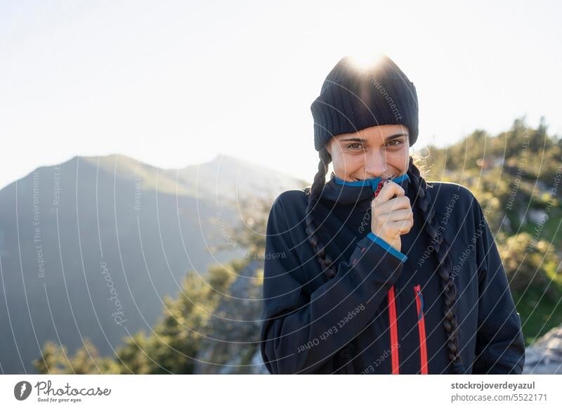 A young woman, mountaineer, sheltered by the cold at the top of a mountain, smile and enjoys the landscape and the moment in nature person mountaineering