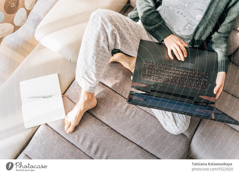 A woman in home clothes with a laptop, next to her is a notebook and a pen Online Internet Lifestyles Laptop female Remote work Note book Wifi Computer