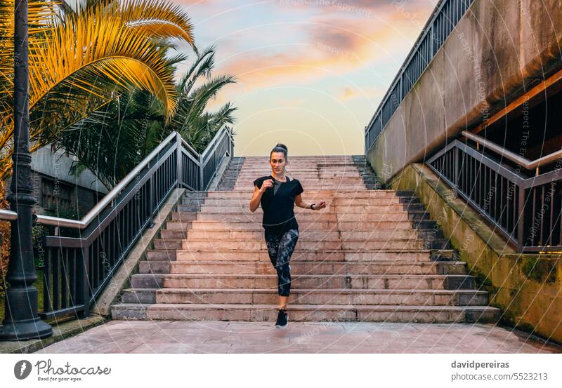 Female runner training down stairs over in urban runway on sunset female happy woman staircase step enjoy smile running sunshine sunrise palm tree leg cardio