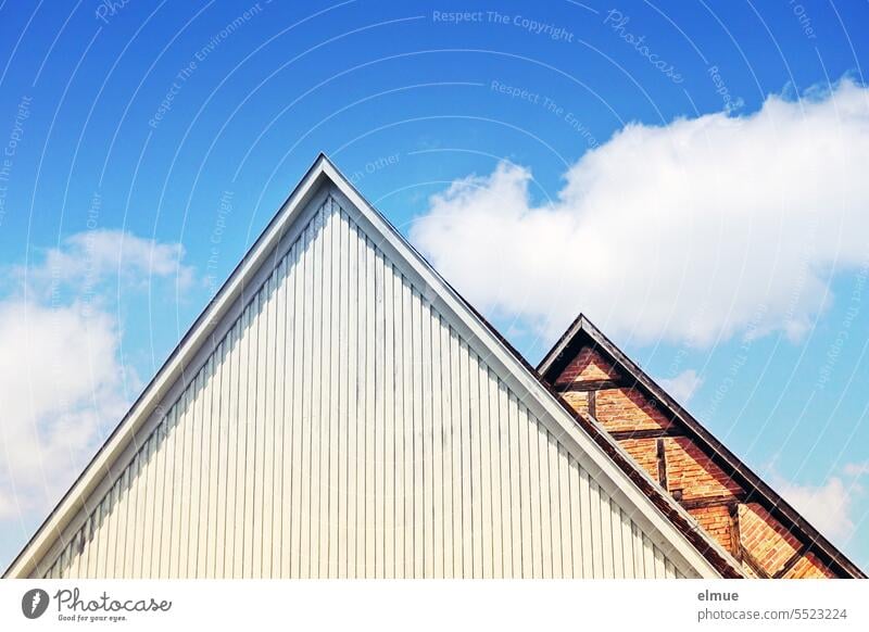 two different windowless roof gables - wood clad and half-timbered against blue sky with fair weather clouds Gable gable wall pediment front