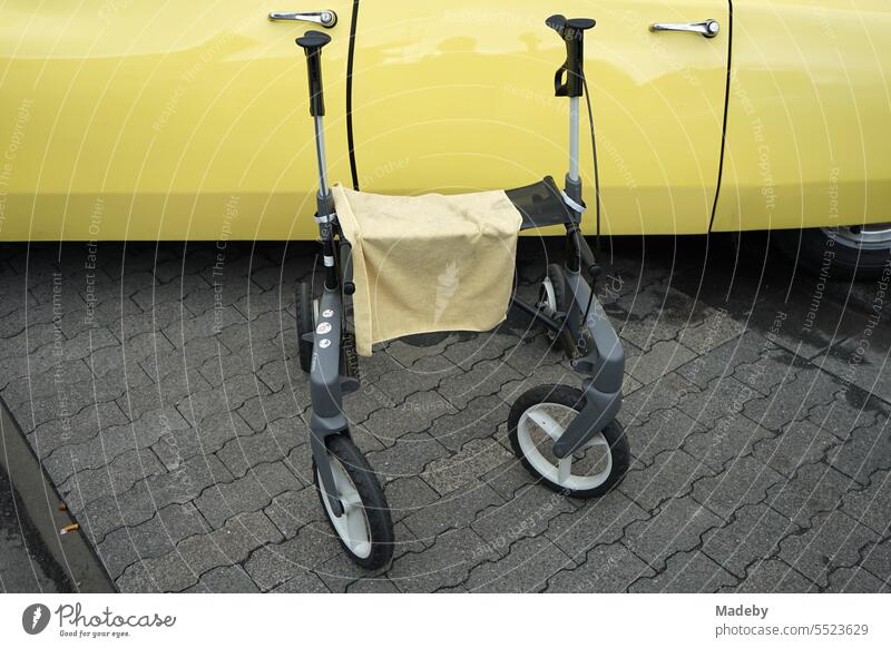 Rollator as a walker with cleaning cloth in yellow and French sedan of the sixties and seventies in the summer at the Oldtimertreffen Golden Oldies in Wettenberg Krofdorf-Gleiberg in Hesse