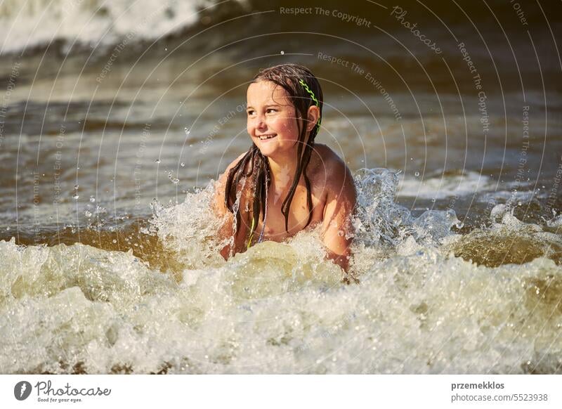 Little girl playing with waves in the sea. Kid playfully splashing with waves. Child jumping in sea waves. Summer vacation on the beach summer vacations ocean