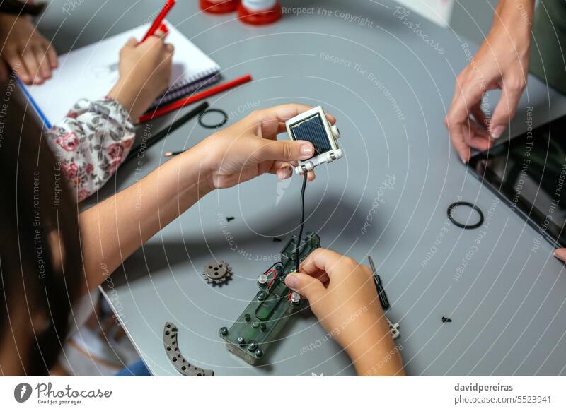 Female student connecting solar panel to electrical circuit in a robotics class unrecognizable female child assemble electronic wire cable technological