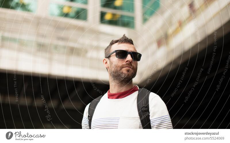 A young, traveling man wearing sunglasses, observes the city and office buildings, during a walk in Spain. person men male adult caucasian portrait lifestyle