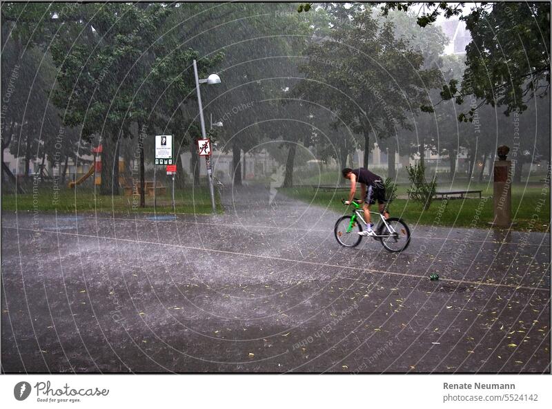 Cyclist in pouring rain street Bicycle cyclists Wheel Sports bike Rain Rain shower Weather Change in the weather Bad weather Park Cycling Outdoors free time