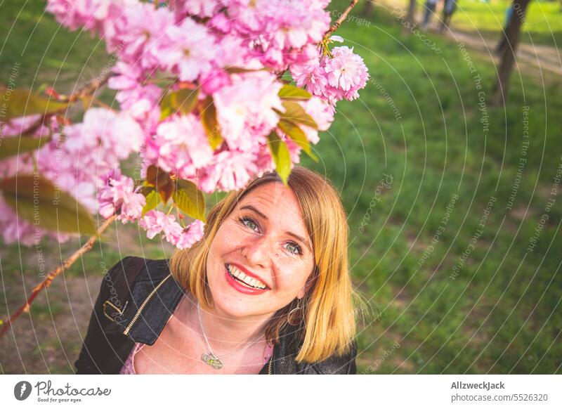 Portrait of smiling young blonde woman next to flowering cherry blossom branch portrait Woman Middle aged woman Young woman blonde hair blonde girl Blonde