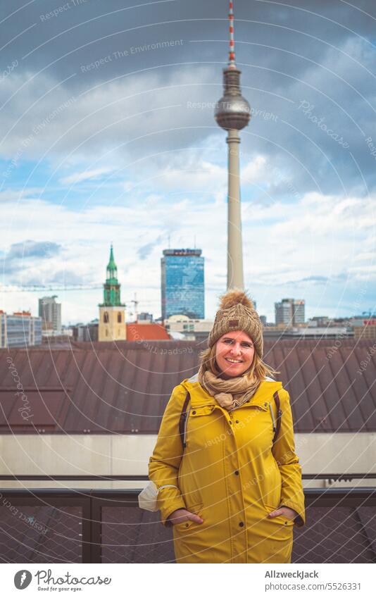 Portrait of young blonde woman with autumn clothes and bobble hat in front of TV tower Berlin Downtown Berlin Berlin TV Tower park inn Hotel Skyline blonde hair