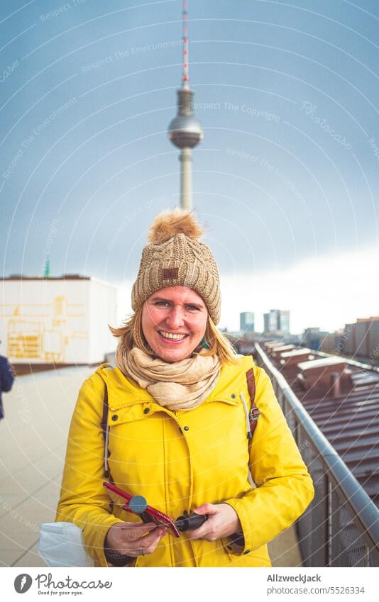 Portrait of young blonde woman with autumn clothes and bobble hat in front of TV tower Berlin Downtown Berlin Berlin TV Tower park inn Hotel Skyline blonde hair