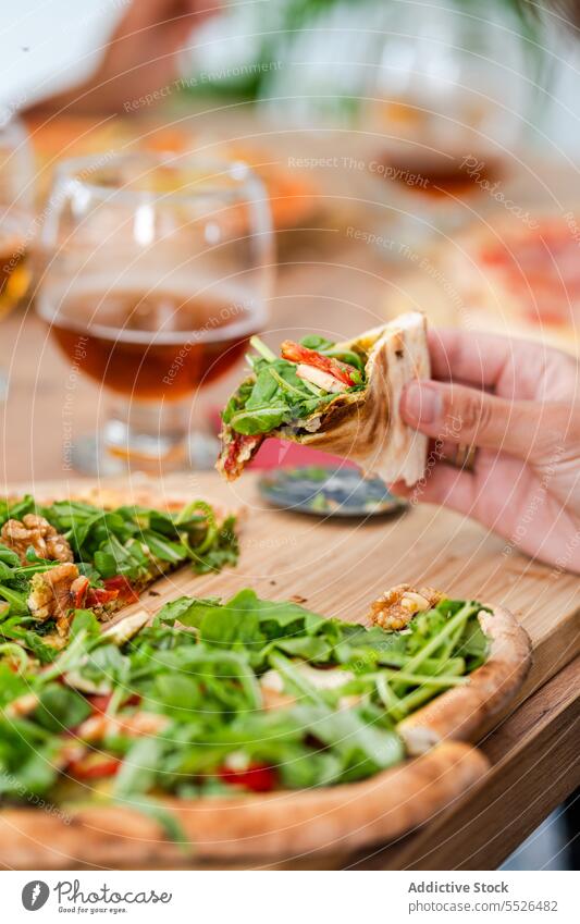 Faceless person eating pizza at table near wineglasses vegetarian lettuce fast food walnut appetizing delicious baked yummy culinary fresh tasty cuisine product