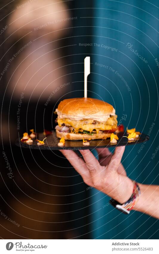 Anonymous person with delicious burger on plate fast food skewer appetizing cheese snack yummy culinary baked fresh tasty cuisine product nutrition delectable