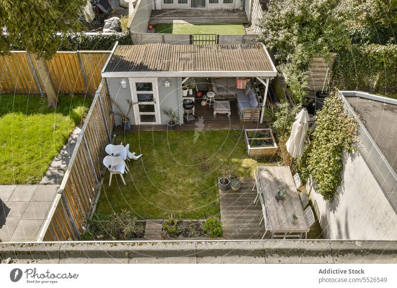 Aerial view of backyard with garden outside small house roof table chair grass plant parasol furniture patio aerial view green residential building meadow grow