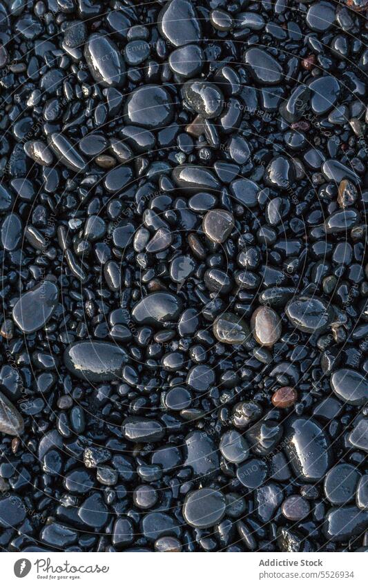 small rocks covered in Reynisfjara Beach pebble sedimentary wet shore evening nature smooth texture background geology stone coast formation countryside boulder