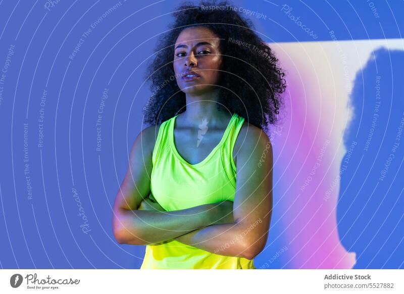 Black woman in headphones standing portrait hand on waist studio shot sport fitness female sportswoman meloman sound activewear wellness sportswear young
