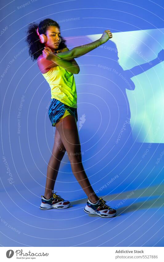 Black woman in headphones standing studio shot sport listen music fitness audio melody female sportswoman black african american ethnic meloman sound activewear