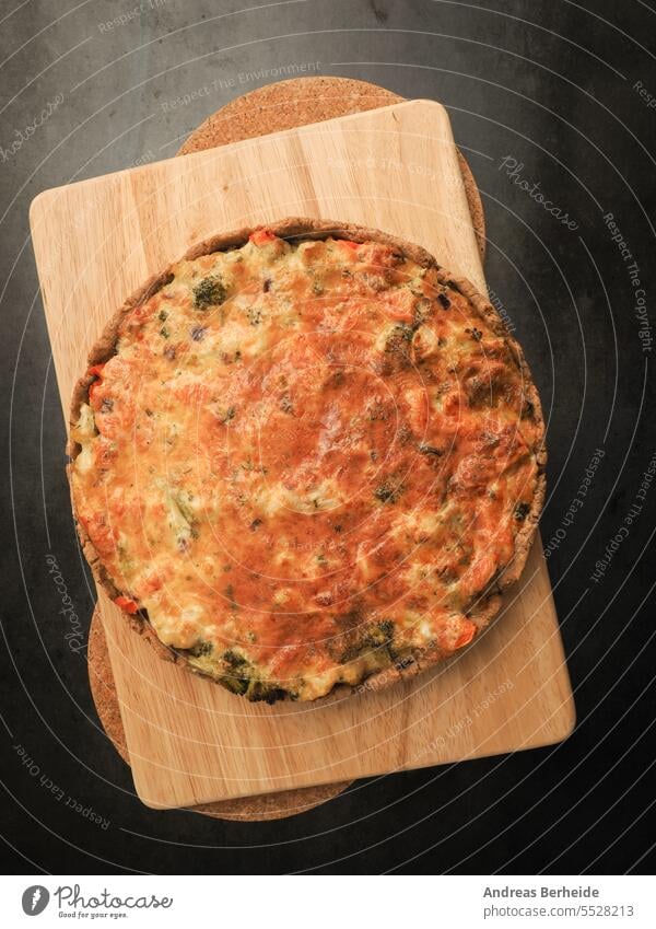 Tasty organic vegetable quiche on a cutting board in a kitchen wooden vegetarian vegetables quiché french pie filled bakery spinach healthy eating lunch cheese